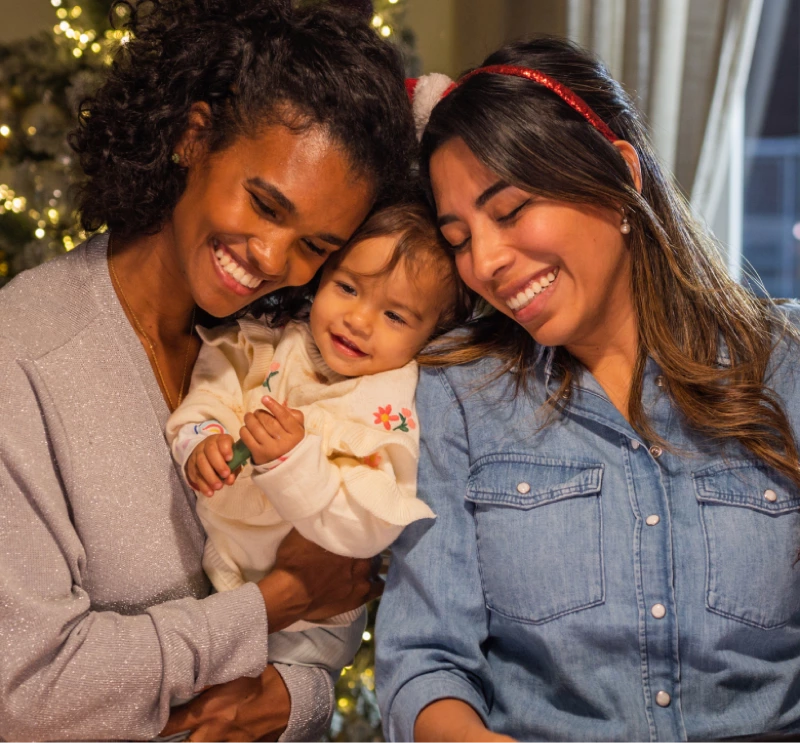 Two women embracing a baby